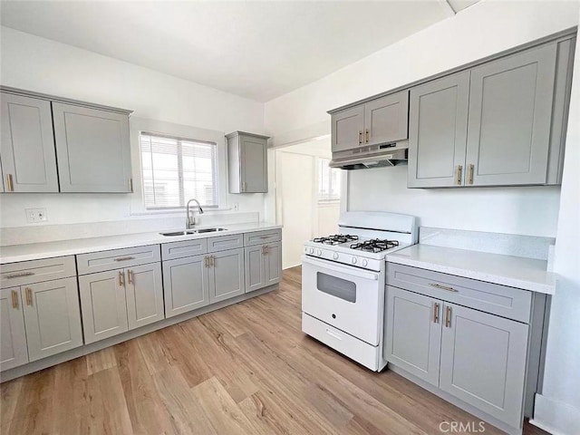 kitchen with sink, light hardwood / wood-style flooring, gray cabinetry, and white gas range oven