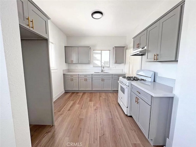 kitchen with sink, gas range gas stove, light hardwood / wood-style floors, and gray cabinets