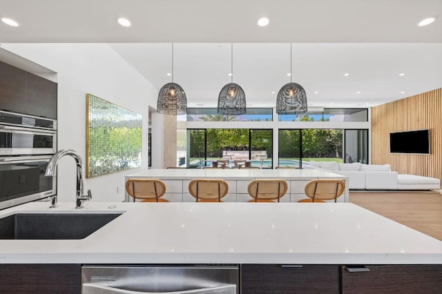 kitchen with dishwasher, dark brown cabinets, sink, and hanging light fixtures