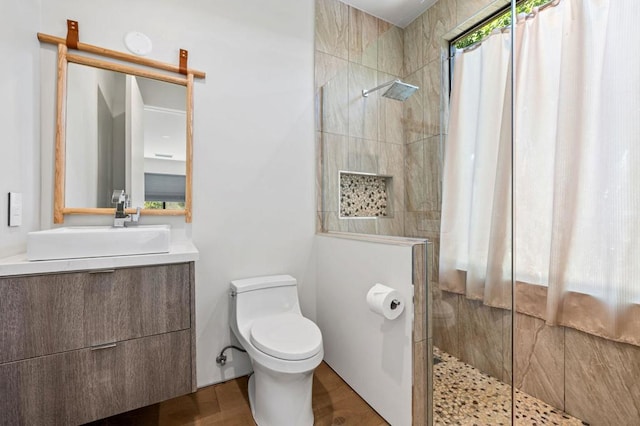 bathroom featuring tiled shower, vanity, and toilet