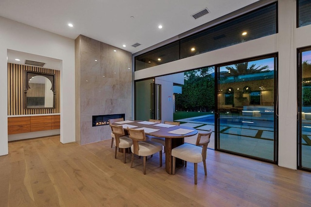 dining room featuring a tile fireplace and light hardwood / wood-style floors