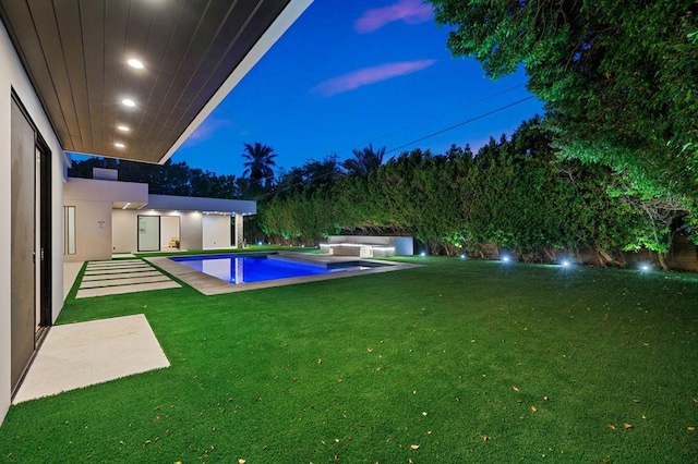 pool at dusk featuring a yard and a patio area