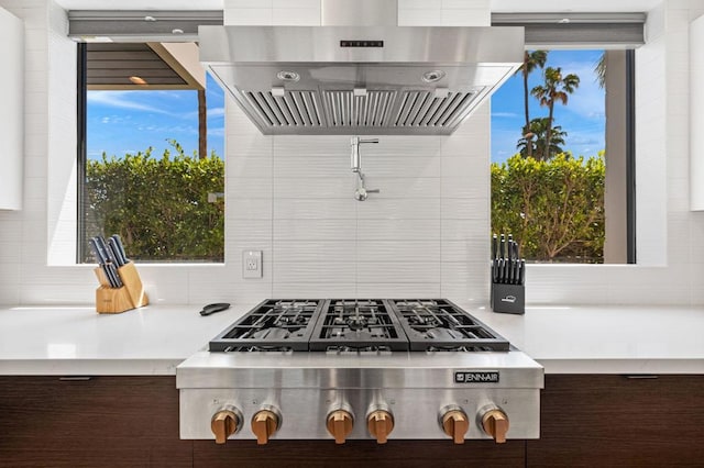 kitchen with dark brown cabinets, wall chimney exhaust hood, and a healthy amount of sunlight