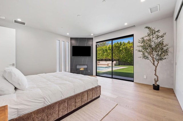 bedroom with a fireplace, access to outside, and light hardwood / wood-style flooring