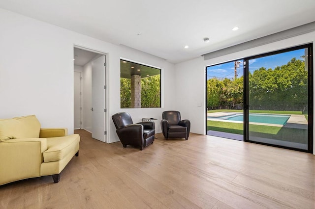 living area featuring plenty of natural light, golf simulator, and light wood-type flooring