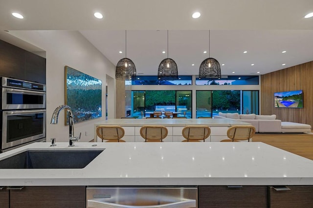 kitchen with pendant lighting, dark brown cabinetry, and sink