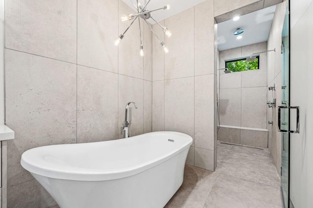 bathroom featuring separate shower and tub, tile walls, and a notable chandelier