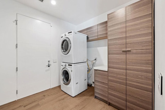 clothes washing area featuring stacked washer / dryer and light hardwood / wood-style floors