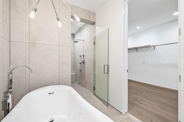 bathroom with hardwood / wood-style flooring, a shower with shower door, and tile walls