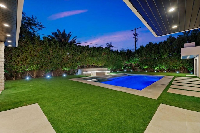 pool at dusk featuring a lawn