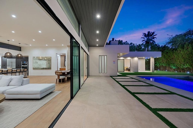 pool at dusk with a patio area