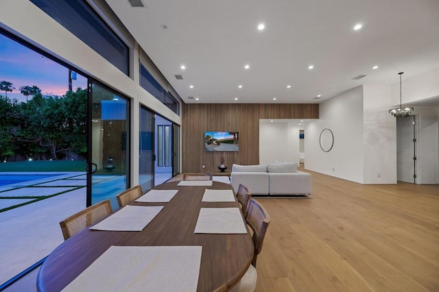 dining room with light hardwood / wood-style floors, an inviting chandelier, and wooden walls