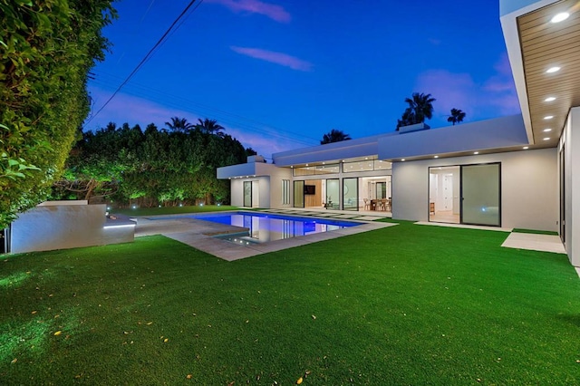 pool at dusk with a yard and a patio