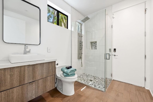 bathroom featuring a shower with door, vanity, wood-type flooring, and toilet