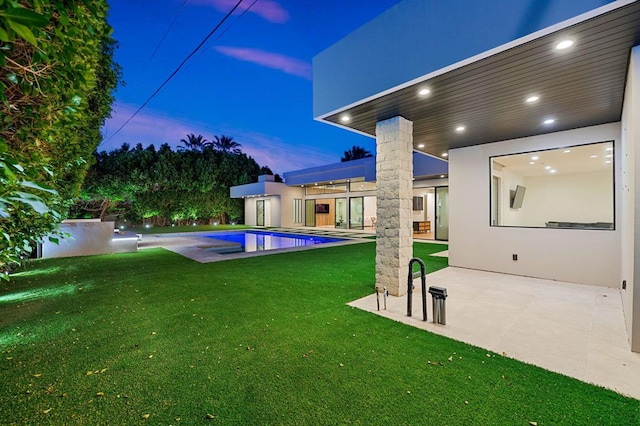 pool at dusk featuring a yard and a patio