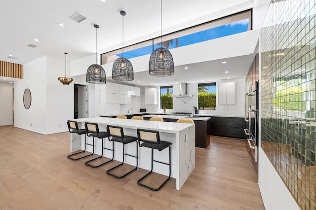 kitchen featuring a spacious island, light hardwood / wood-style flooring, white cabinets, and hanging light fixtures