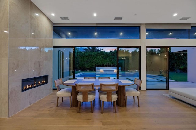 dining room with a tile fireplace and light hardwood / wood-style flooring