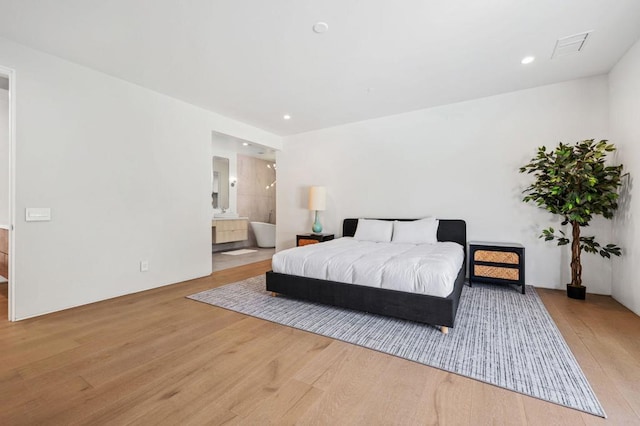 bedroom with connected bathroom and light hardwood / wood-style floors