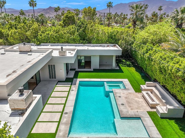 back of property featuring a patio area, a mountain view, and a yard