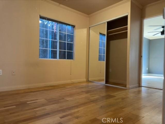 unfurnished bedroom featuring a closet, hardwood / wood-style floors, and ornamental molding