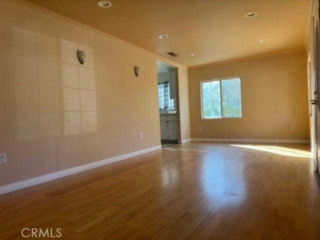 spare room with hardwood / wood-style floors and crown molding