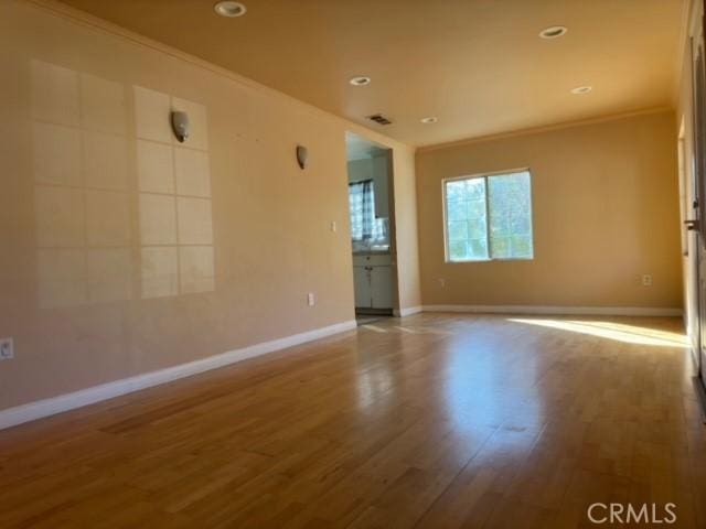 unfurnished room with hardwood / wood-style floors and ornamental molding