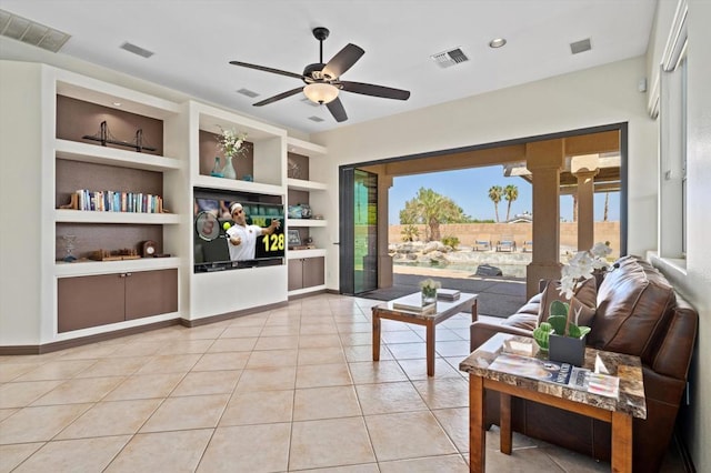 living room with built in shelves, ceiling fan, and light tile patterned floors