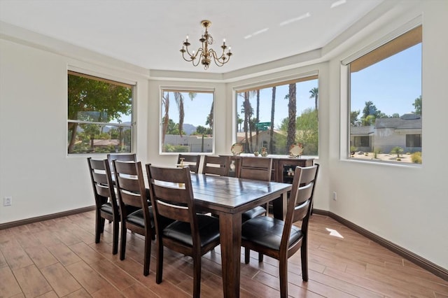 dining space with light hardwood / wood-style floors and an inviting chandelier