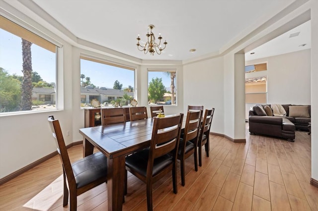 dining space with light wood-type flooring and an inviting chandelier