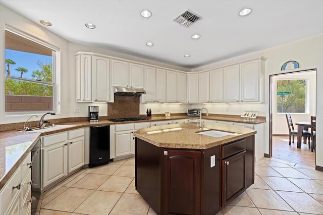 kitchen featuring light tile patterned flooring, light stone counters, and sink