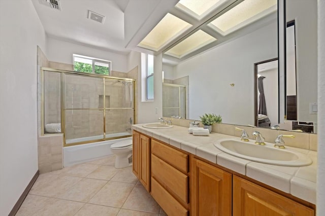 full bathroom featuring shower / bath combination with glass door, tile patterned floors, vanity, and toilet