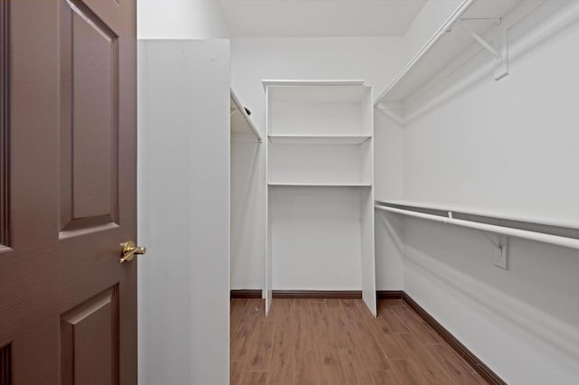 walk in closet with light hardwood / wood-style floors