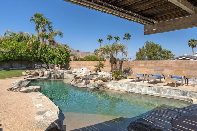 view of pool with pool water feature, a mountain view, and a patio