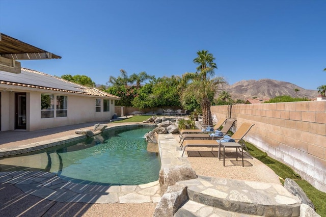 view of swimming pool with pool water feature, a mountain view, and a patio area