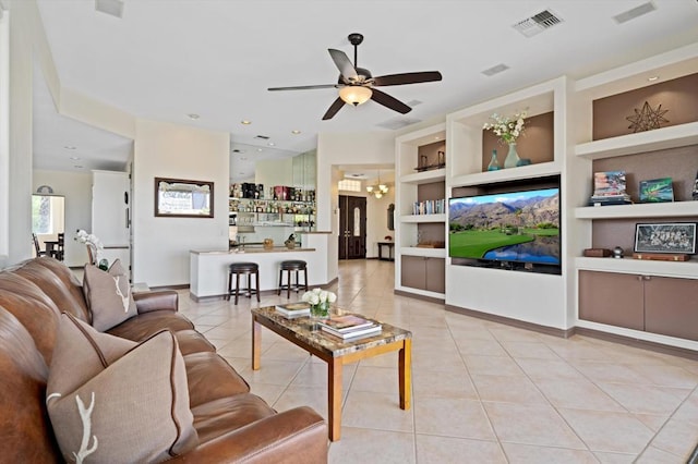 living room with light tile patterned floors, ceiling fan with notable chandelier, and built in features