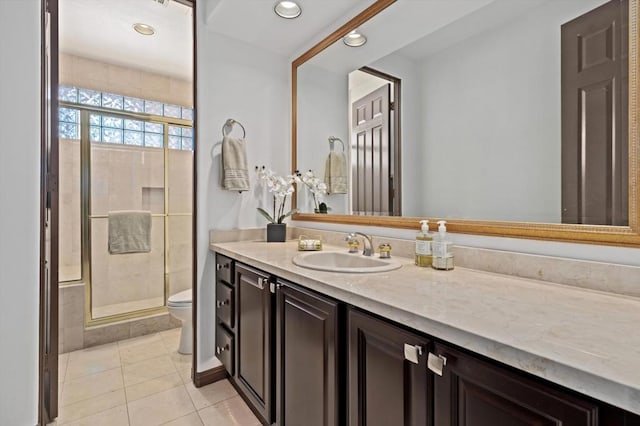 bathroom with toilet, vanity, tile patterned floors, and a shower with shower door