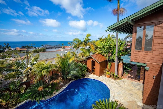 view of pool with a storage unit, a water view, and a patio