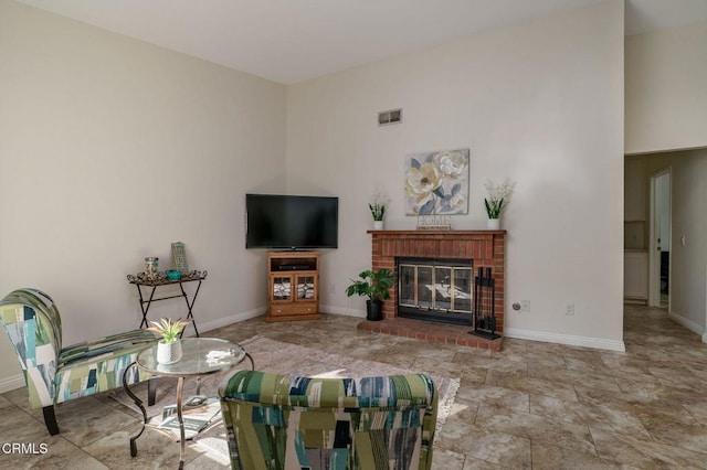 living area featuring baseboards, visible vents, and a brick fireplace