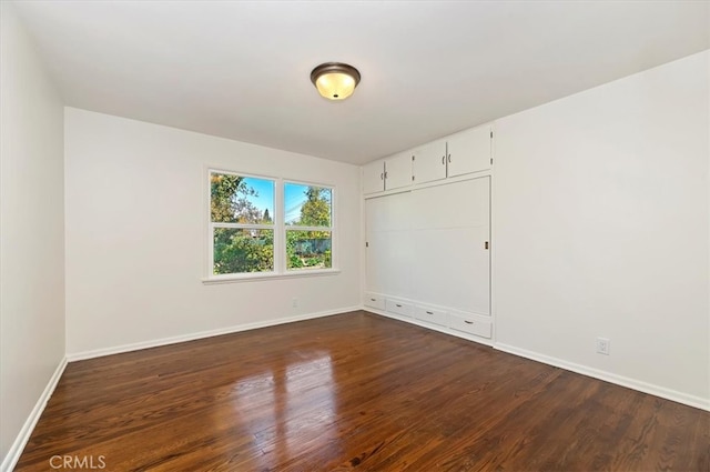 unfurnished room with dark wood-type flooring