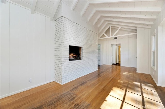 unfurnished living room featuring hardwood / wood-style flooring, vaulted ceiling with beams, and a fireplace