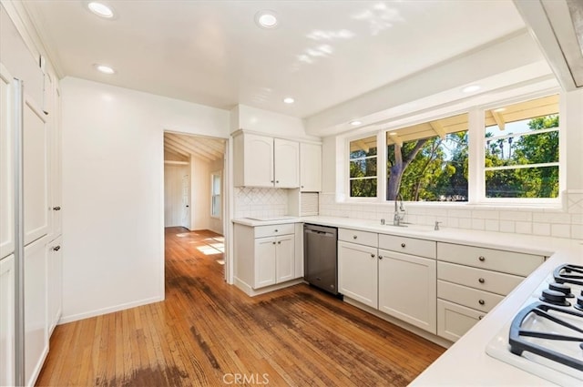 kitchen with wood-type flooring, sink, backsplash, stainless steel dishwasher, and white cabinets