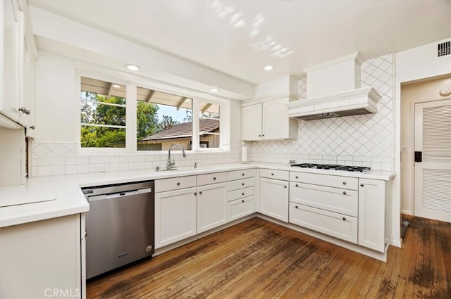 kitchen featuring dark wood-type flooring, custom range hood, backsplash, stainless steel dishwasher, and white cabinets