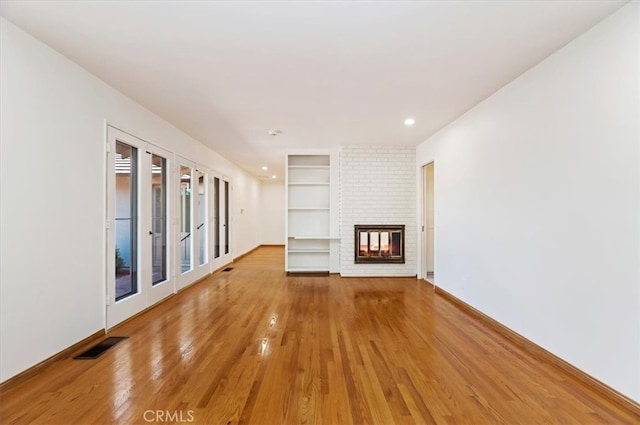 unfurnished living room with a brick fireplace and hardwood / wood-style flooring