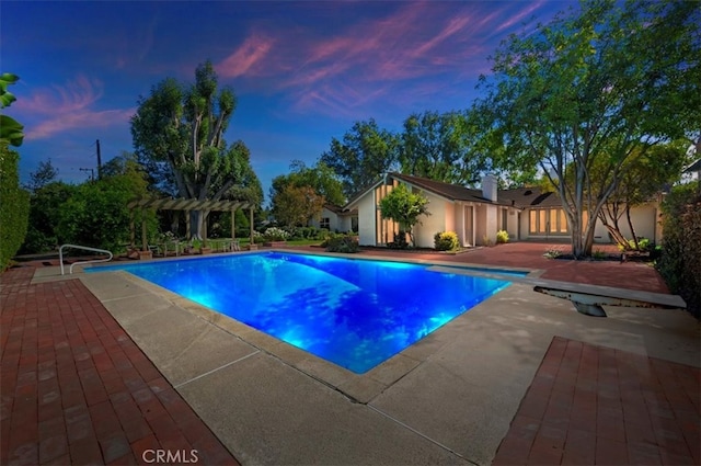 pool at dusk with a patio area