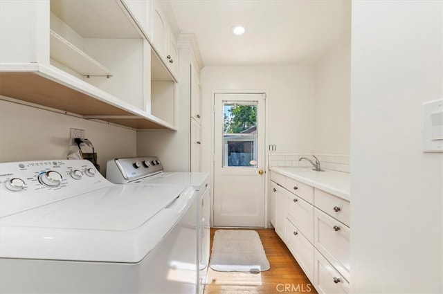 laundry room featuring cabinets, sink, washing machine and clothes dryer, and light wood-type flooring