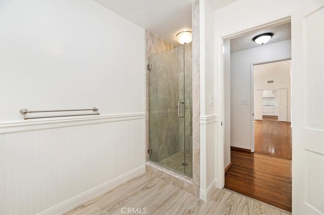 bathroom with wood-type flooring and a shower with shower door