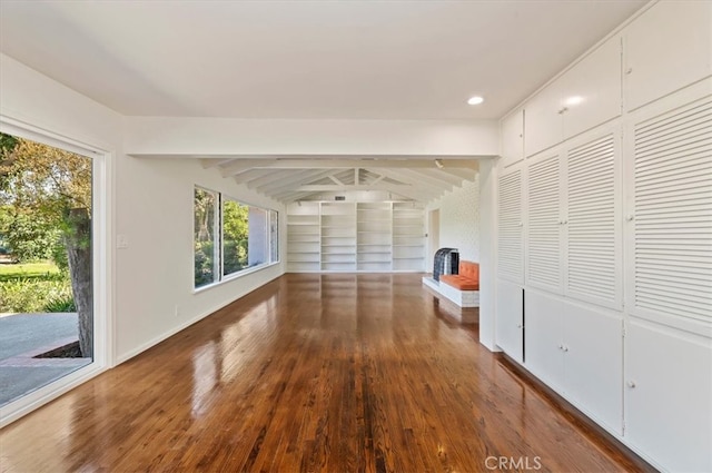 unfurnished living room featuring beam ceiling and dark wood-type flooring