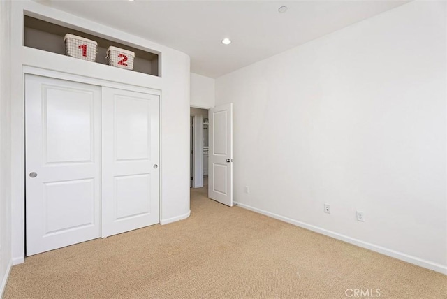 unfurnished bedroom featuring light colored carpet and a closet