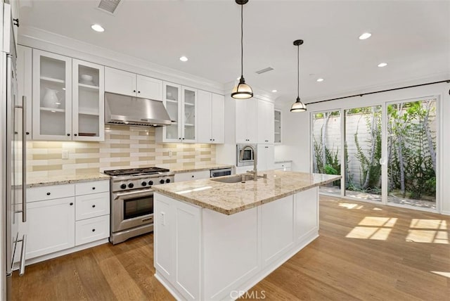 kitchen featuring light wood-type flooring, premium appliances, a kitchen island with sink, sink, and white cabinets