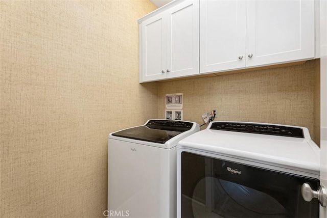 laundry room with washing machine and clothes dryer and cabinets